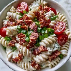 Close-up handheld photo of BLT Pasta Salad showing the glossy ranch dressing and jagged bacon lardons. (BLT Pasta Salad)