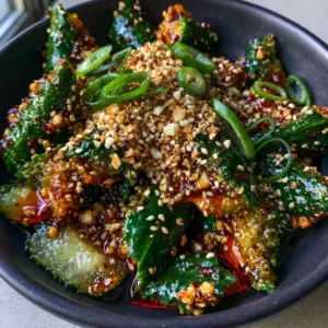 Close up photo of jagged Persian cucumbers with translucent red chili oil and dark soy dressing. (cucumber salad recipes)